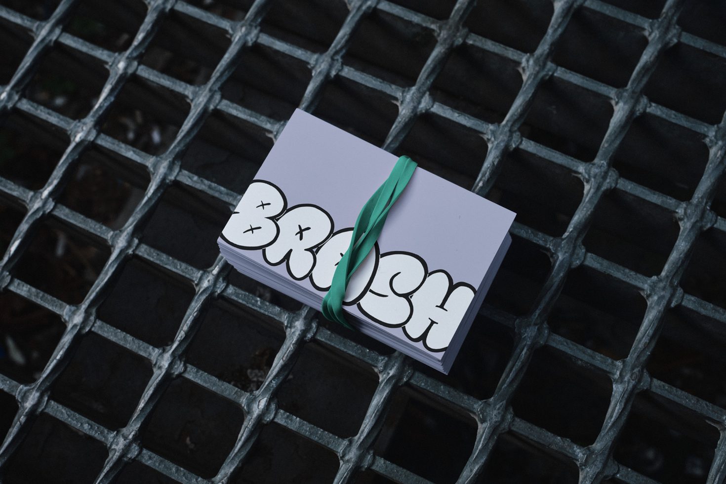 Stack of purple cards with graffiti style text Brush wrapped in green ribbon placed on a metal grate, ideal for graphics and branding design projects